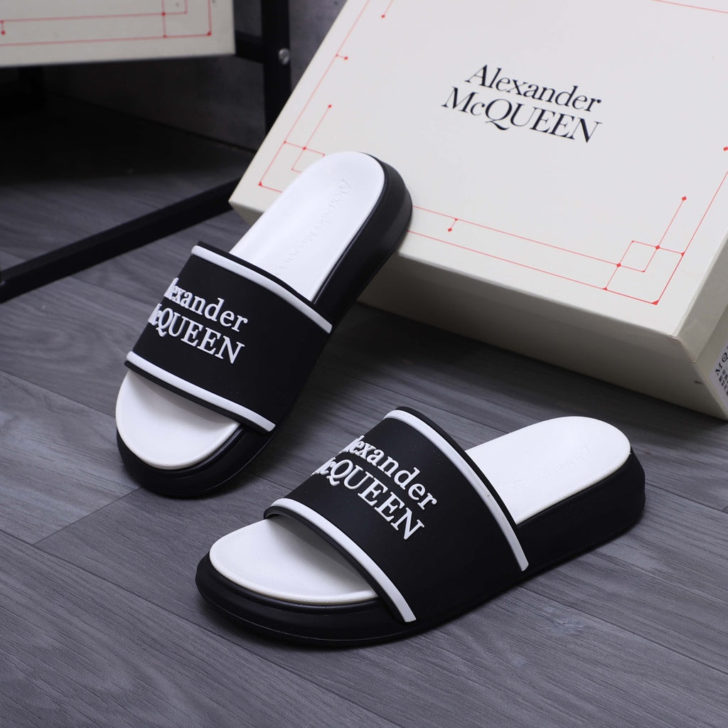 Pair of black slide sandals with white footbeds and Alexander McQueen logo
