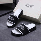 Pair of black slide sandals with white footbeds and Alexander McQueen logo