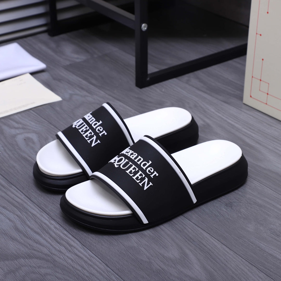 Black slide sandals with wide white band and Alexander McQueen logo