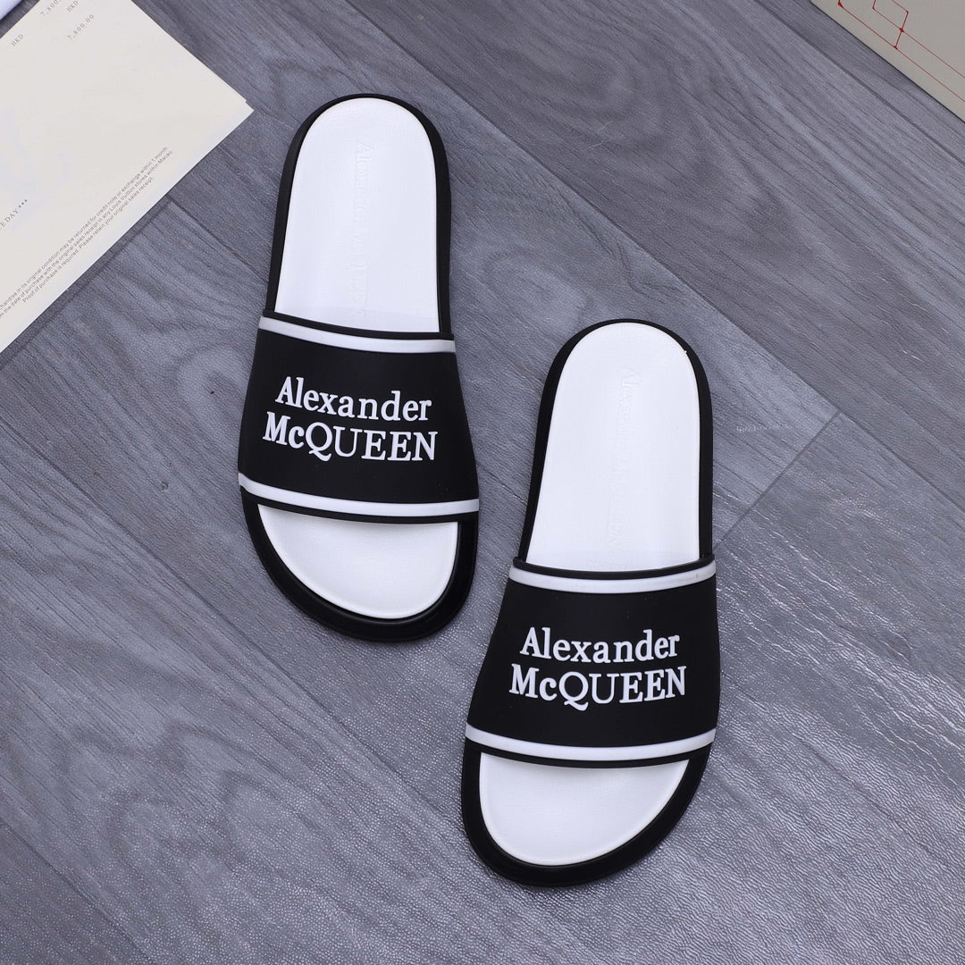 Two white slide sandals with black Alexander McQueen logo band and trim