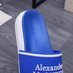 Blue slide sandal showing footbed with Alexander McQUEEN embossed text and white sole