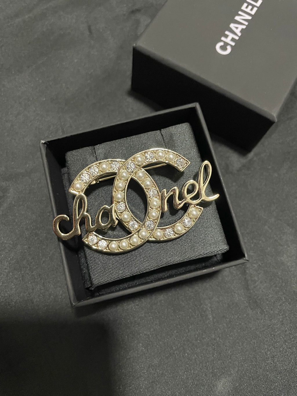 Gold-tone Chanel brooch with pearl and crystal accents, full script logo view