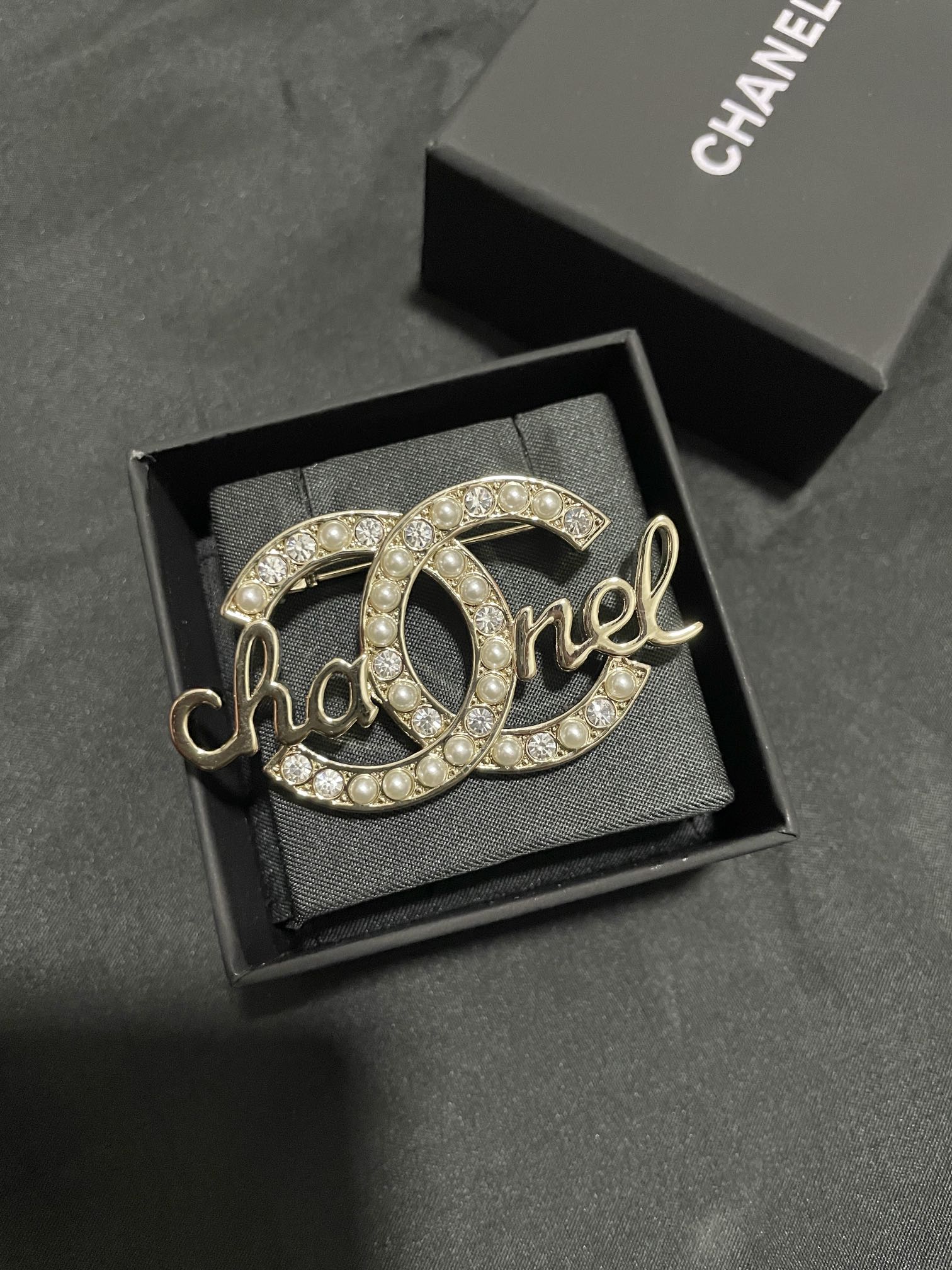 Gold-tone Chanel brooch with pearl and crystal accents, full script logo view