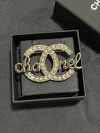 Gold-tone Chanel brooch with pearl and crystal accents, script logo detail