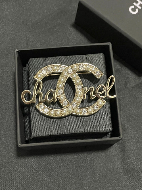 Gold-tone Chanel brooch with pearl and crystal accents, script logo detail