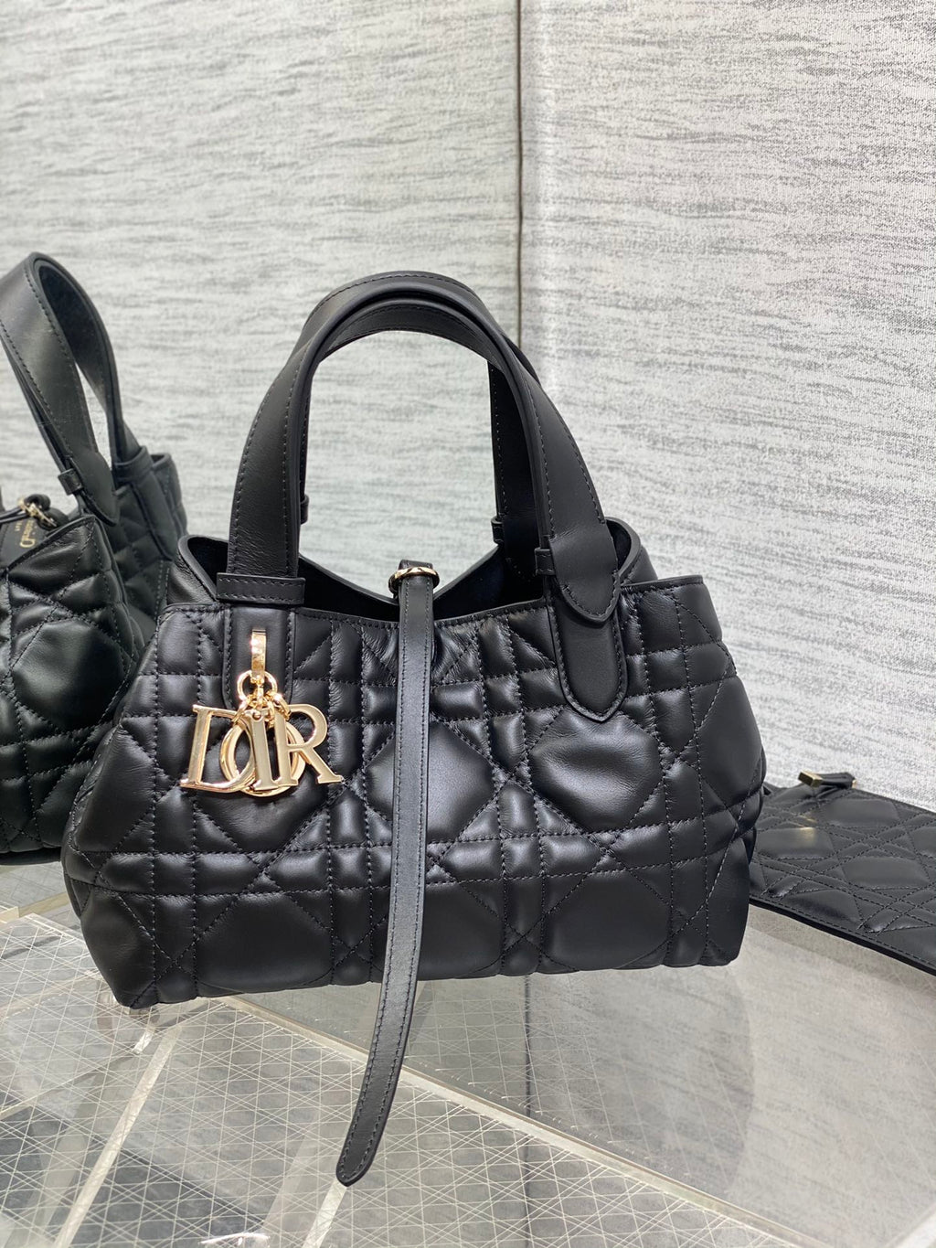Quilted black Dior handbag with top handles and gold-tone logo charm