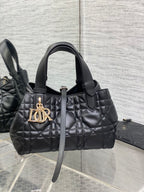 Quilted black Dior handbag with top handles and gold-tone logo charm