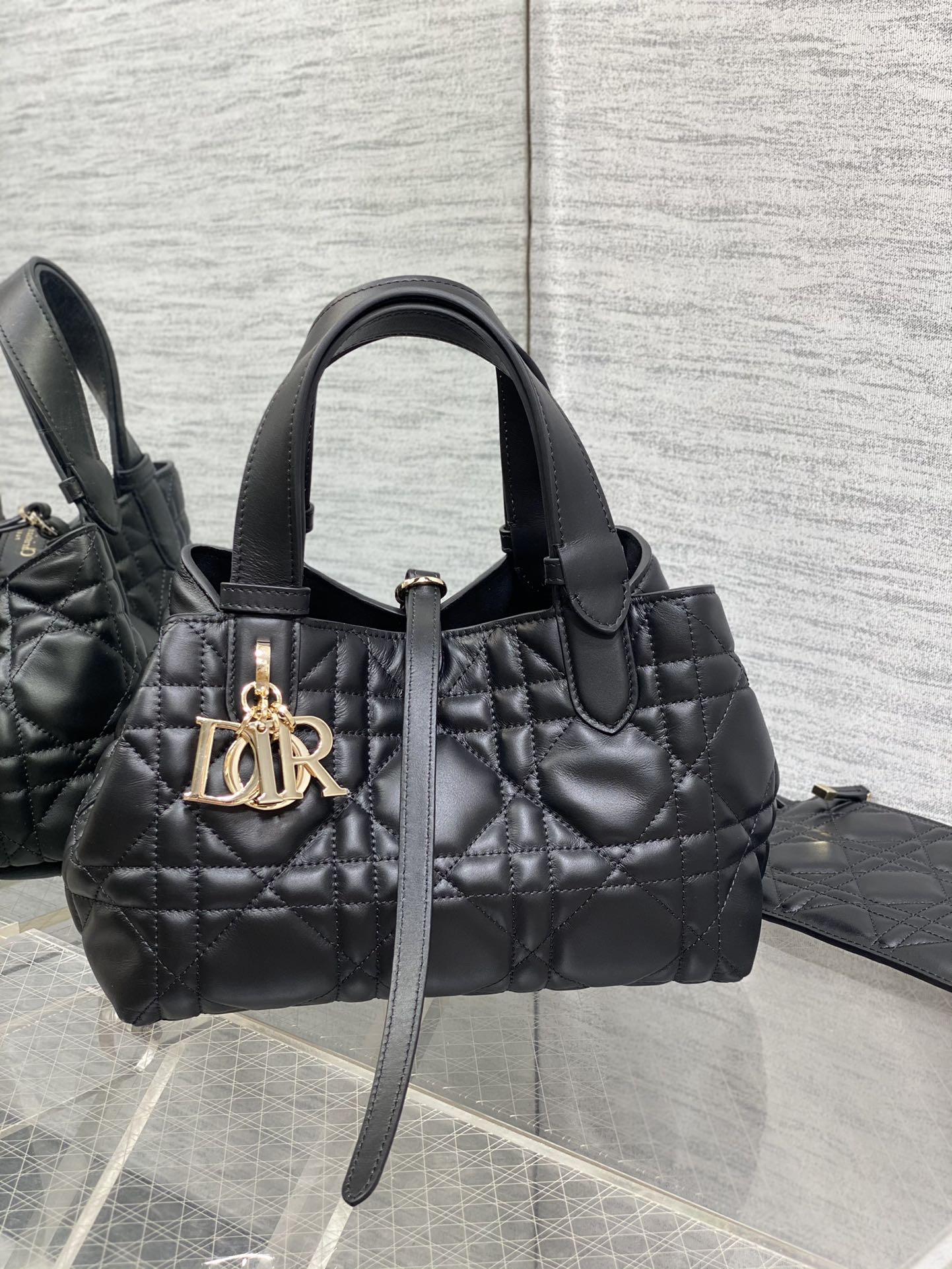 Quilted black Dior handbag with top handles and gold-tone logo charm