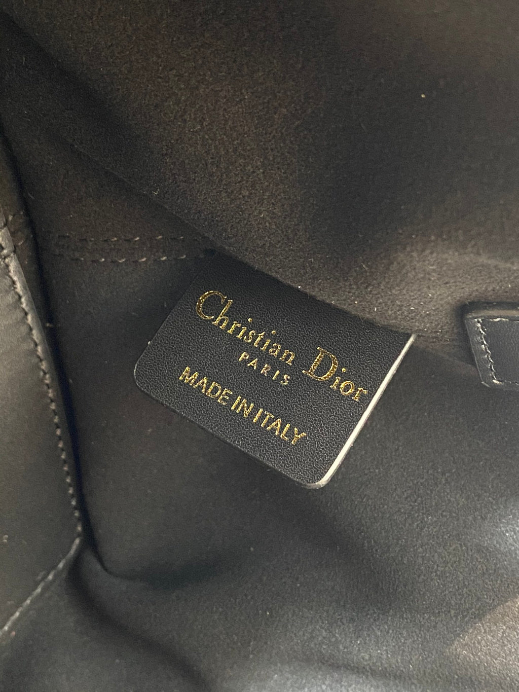 Black leather Dior tag reading 'Christian Dior Paris' and 'Made in Italy'