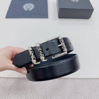 Dark leather belt with silver clasp and engraved decorative hardware, close-up