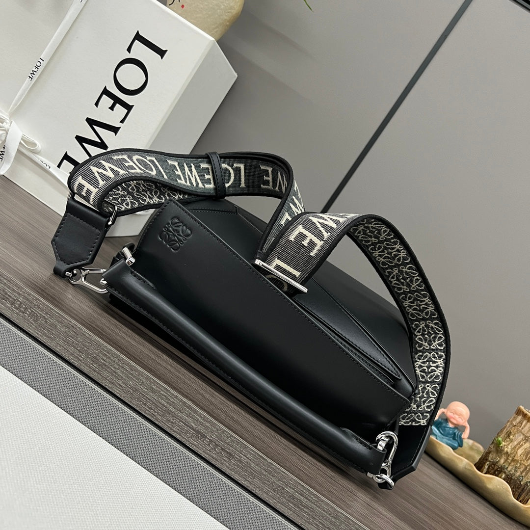 Black top-handle bag with jacquard strap, silver hardware, and front emblem.