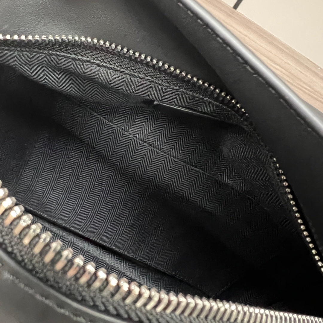Black fabric-lined interior of a bag with zipper teeth and trim.