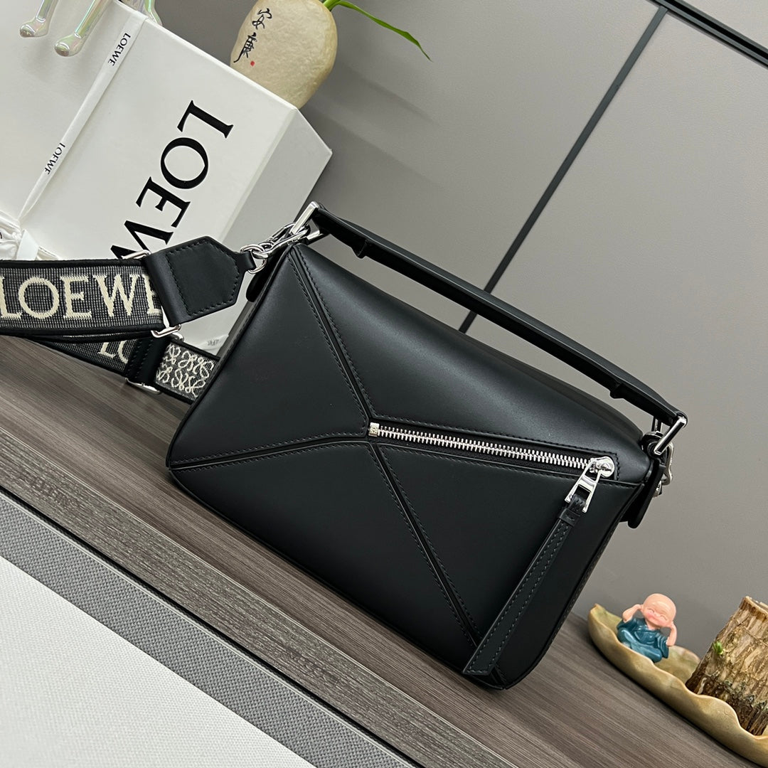 Black leather top-handle bag with front zipper and logo strap detail.