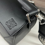 Close-up of black leather bag with embossed logo and silver clasp hardware.