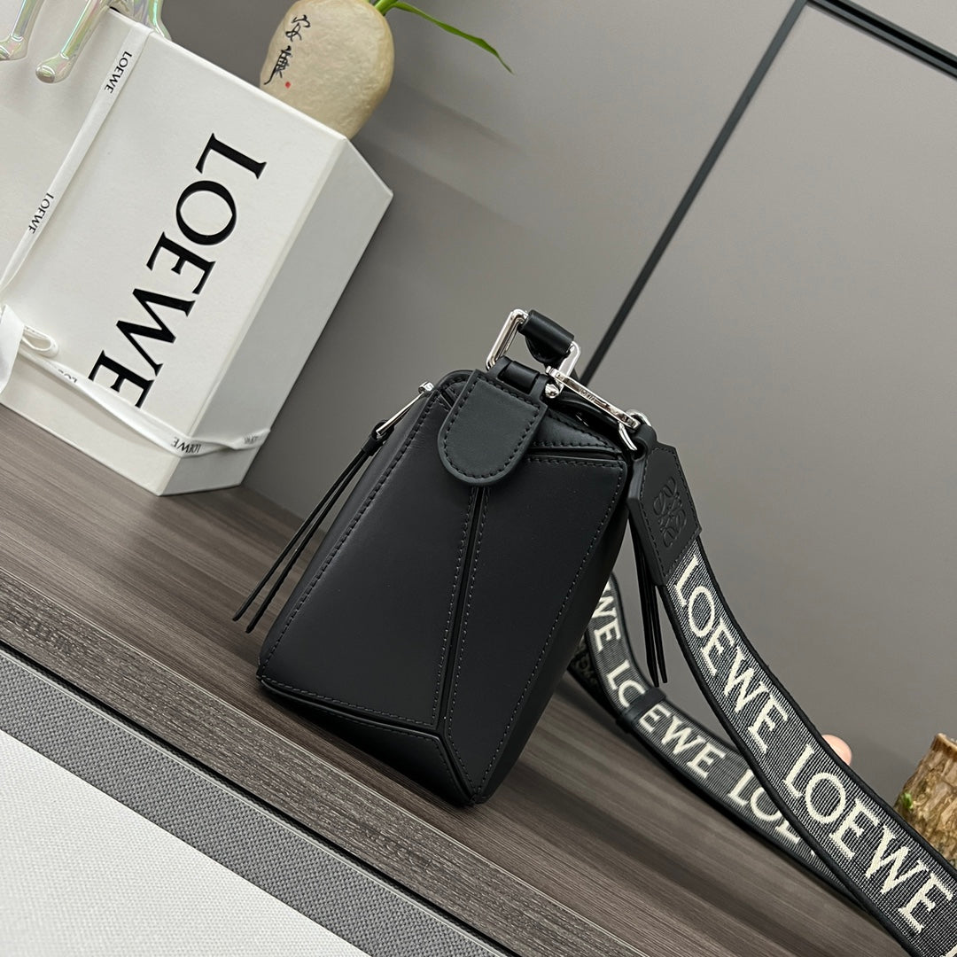 Black leather top-handle bag with flap closure, silver buckle, and strap.