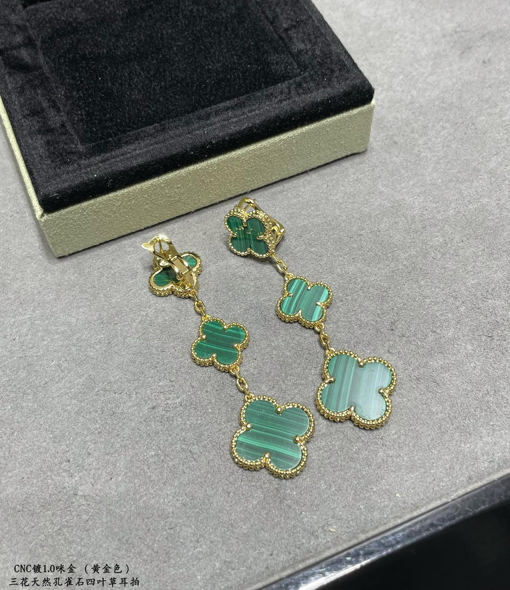 Clover drop earrings with green enamel and gold-tone chain, angled view on display