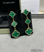 Clover drop earrings with green enamel and gold-tone chain, on black velvet holder