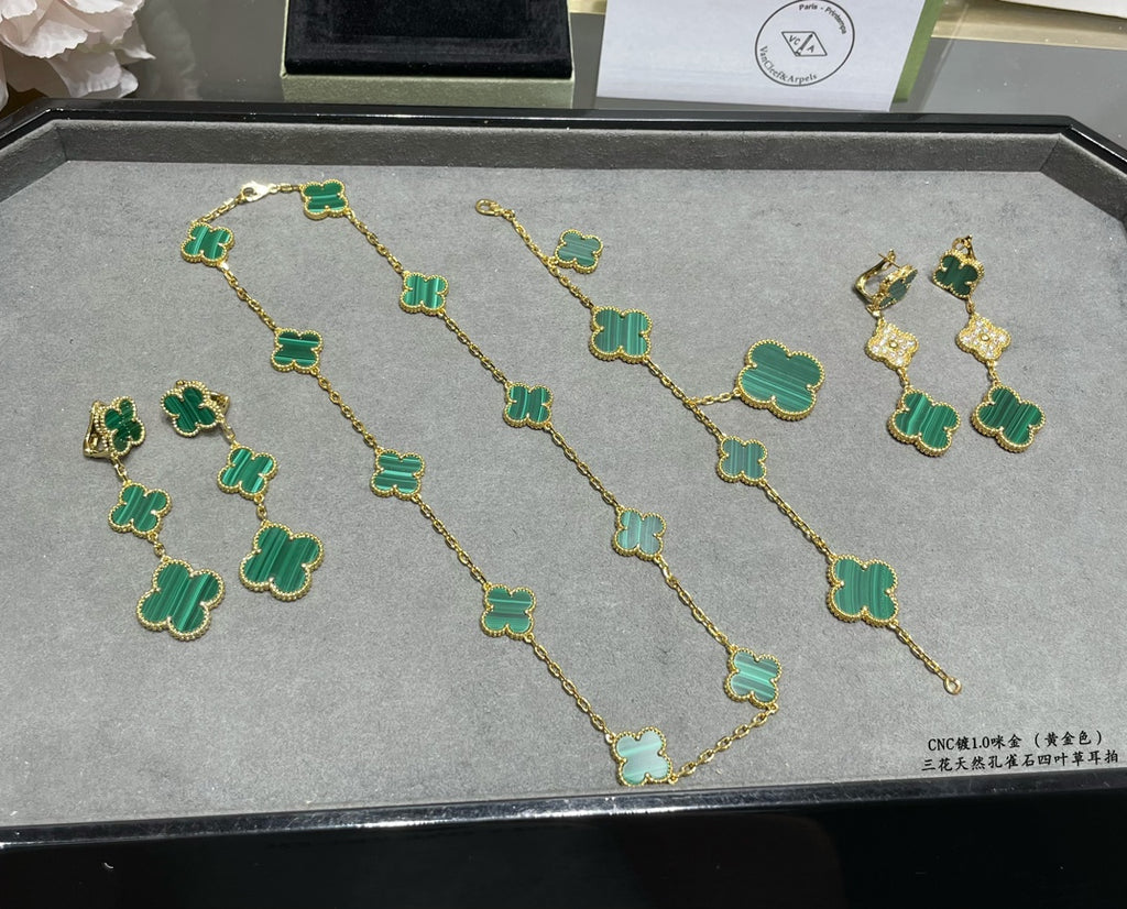 Clover chain necklace with green enamel motifs, laid out on tray