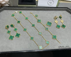 Clover chain necklace with green enamel motifs, laid out on tray