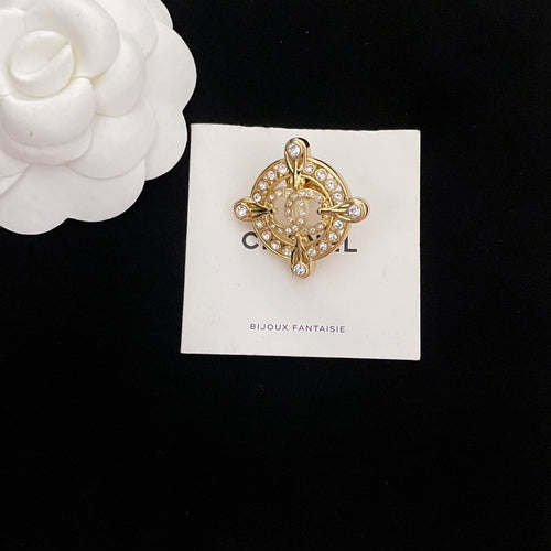 Gold-tone rhinestone Chanel brooch, circular center with quatrefoil arms