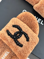 Close-up of tan teddy slide upper with black beaded CC-style logo