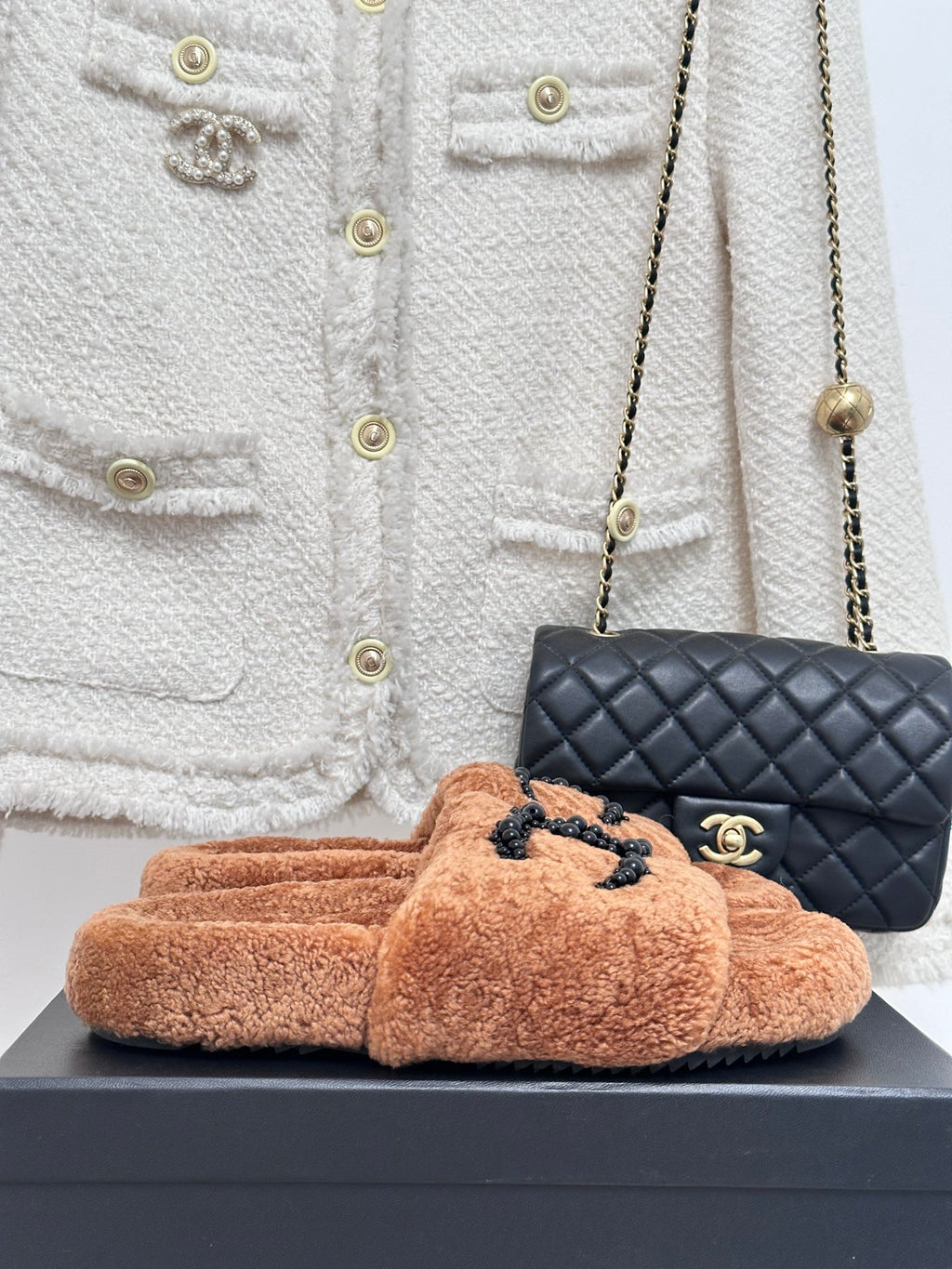 Tan teddy slide sandals with black beaded CC logo on upper