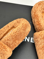 Close-up of tan teddy slide sandals with CHANEL logo on inner footbed