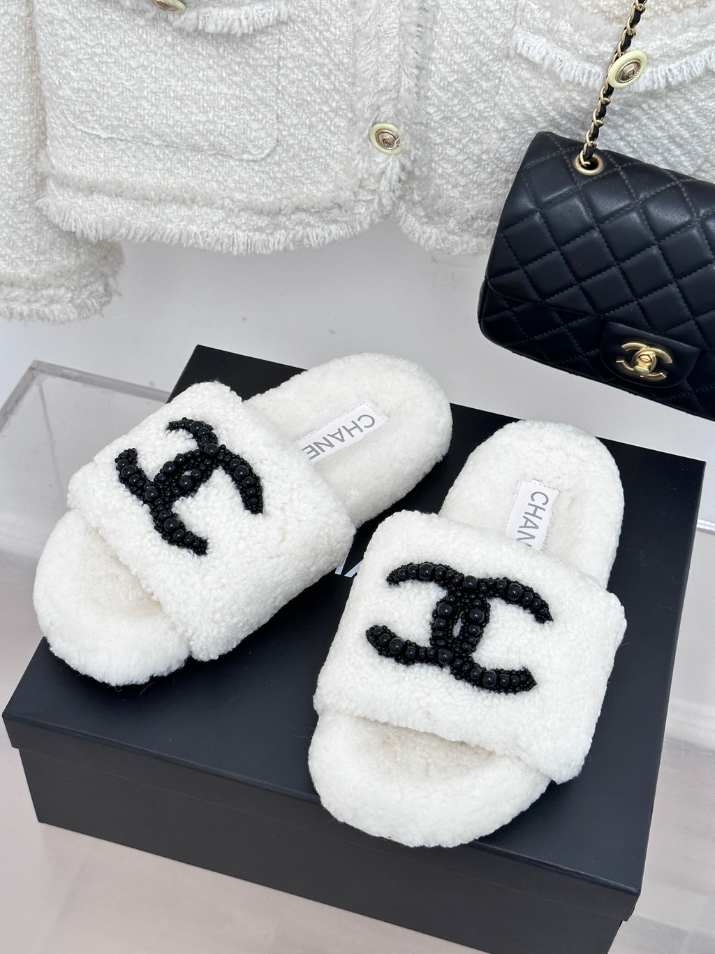 Chanel white fuzzy slides with black CC emblem, pair on display