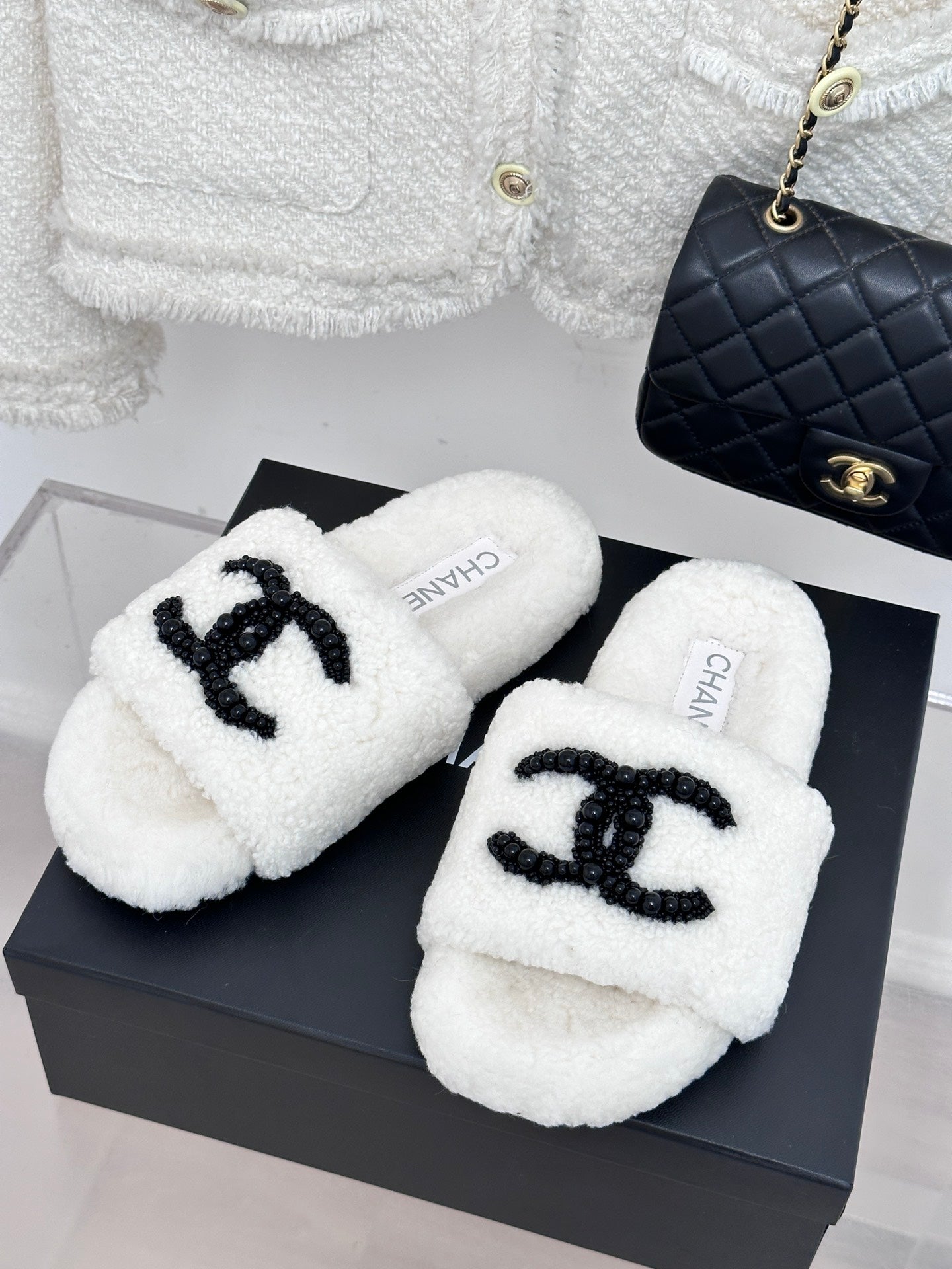 Chanel white fuzzy slides with black CC emblem, pair on display