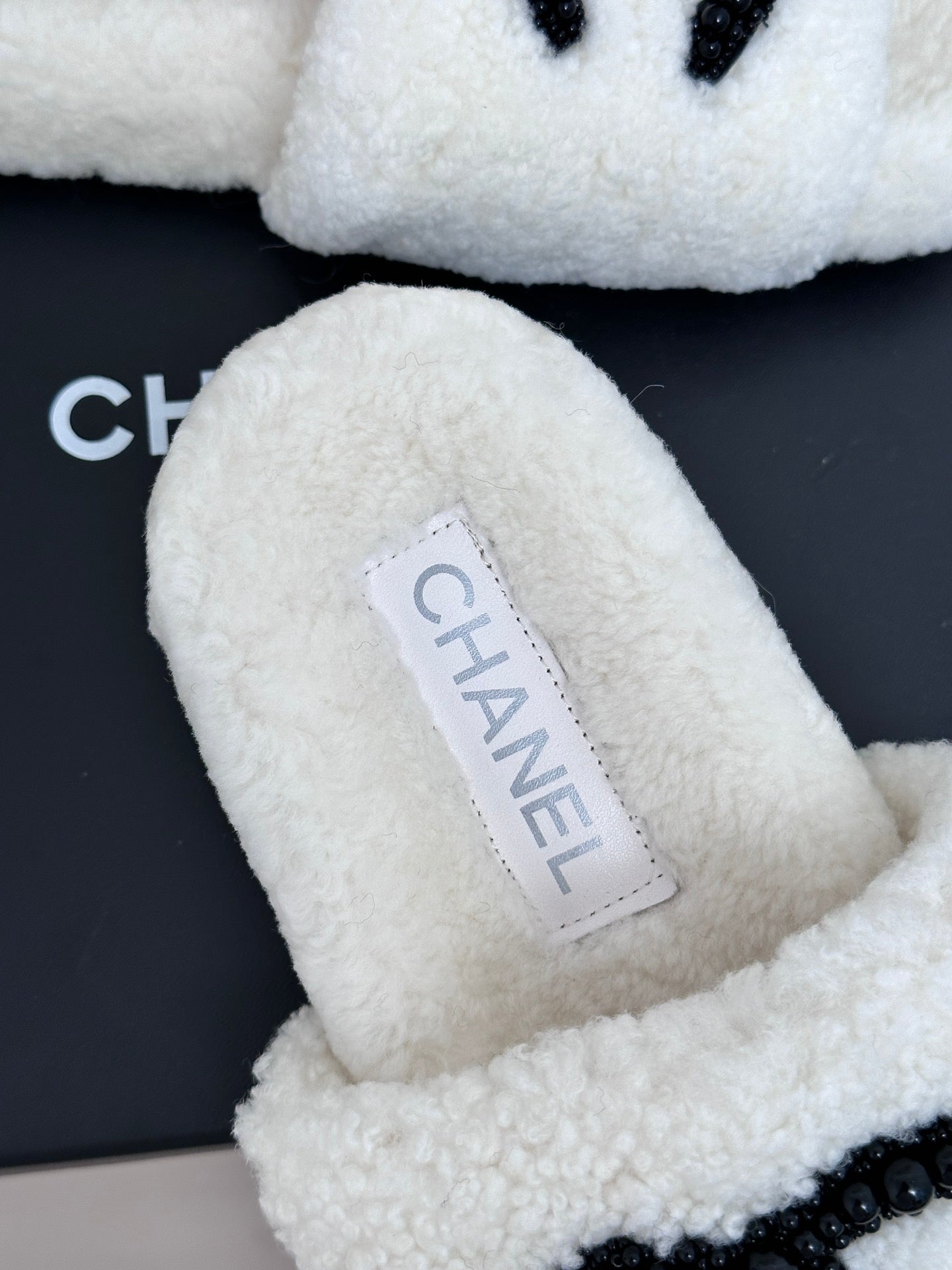 Chanel white fuzzy slides with brand label patch and black CC emblem