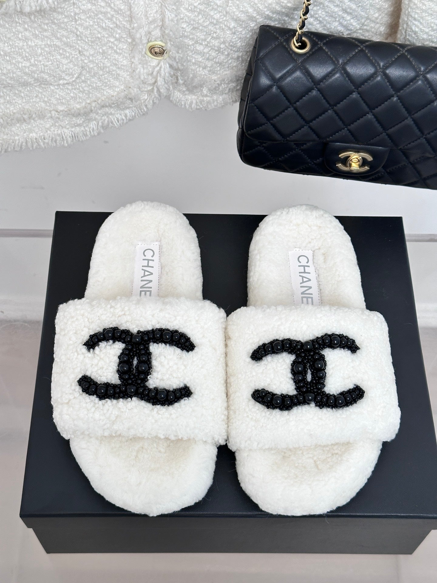 Chanel white fuzzy slides with black CC emblem, front view pair on box