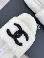 Chanel white fuzzy slides with black CC emblem, close-up logo detail