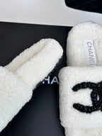 Chanel white fuzzy slides with black CC emblem, close-up side view