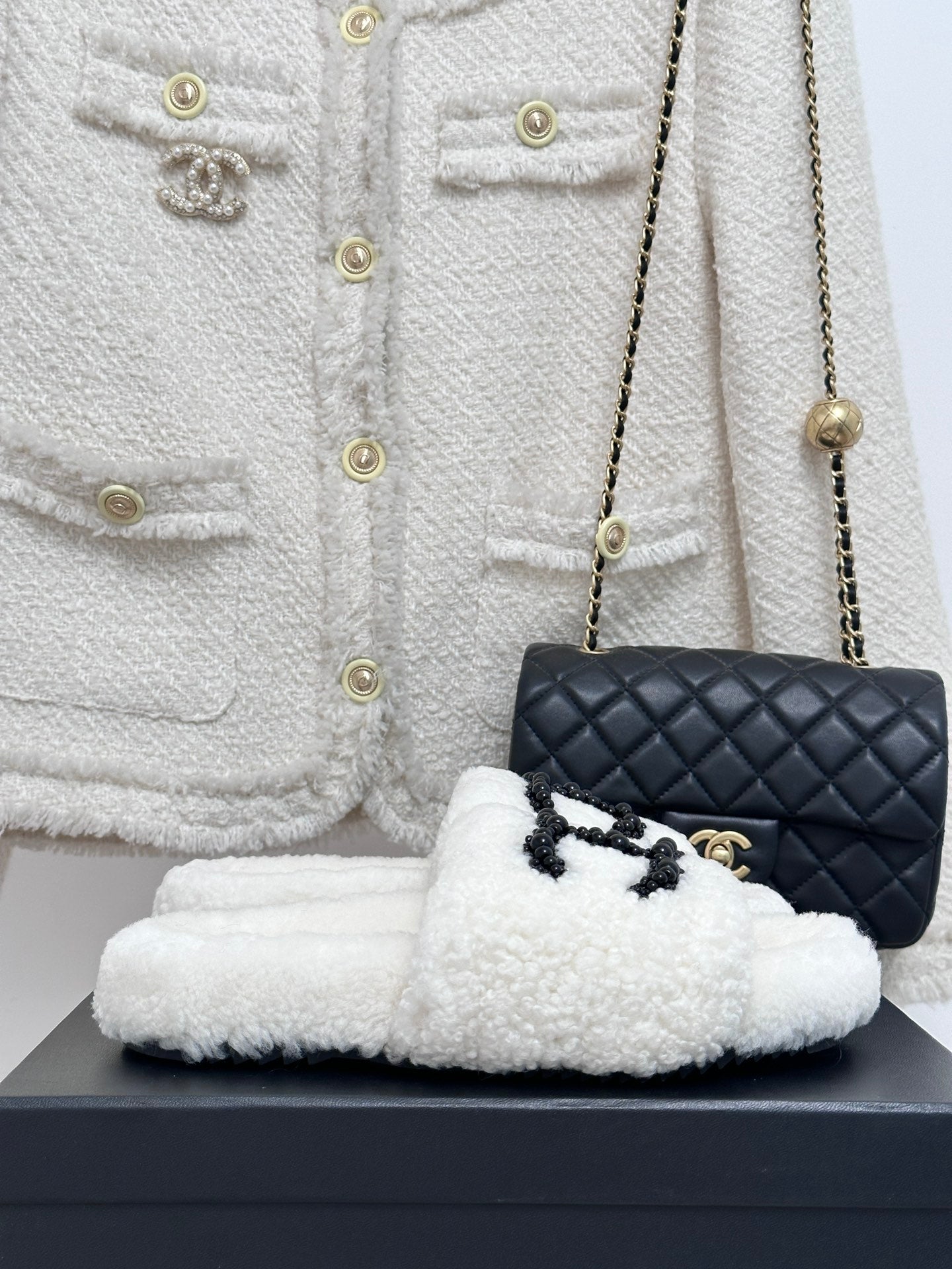 Chanel white fuzzy slip-on slides with black CC emblem, cushioned sole
