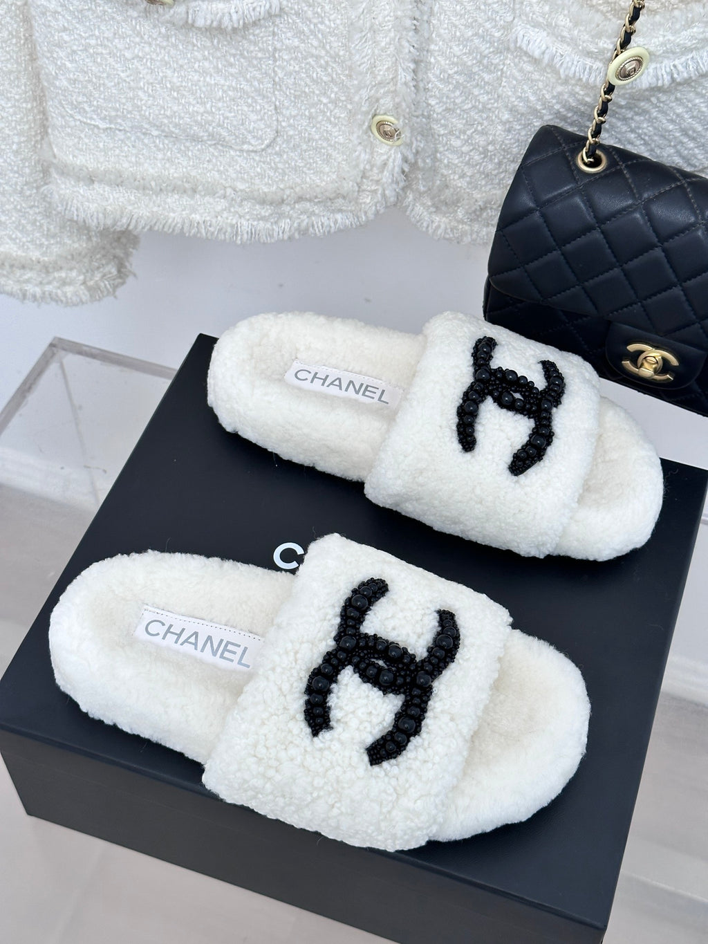 Chanel white fuzzy slip-on slides with black CC emblem, two shoes on box