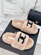 Pair of beige plush slides with black beaded logo on top, womens luxury shoes