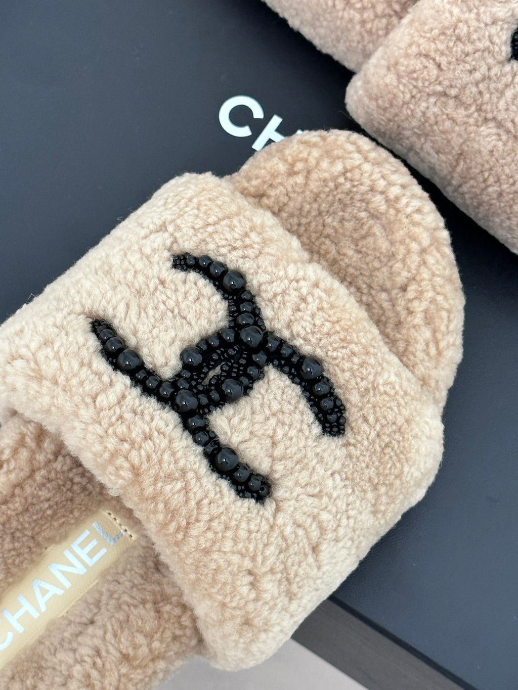 Beige plush slide with black beaded logo embroidery on top, womens luxury shoes