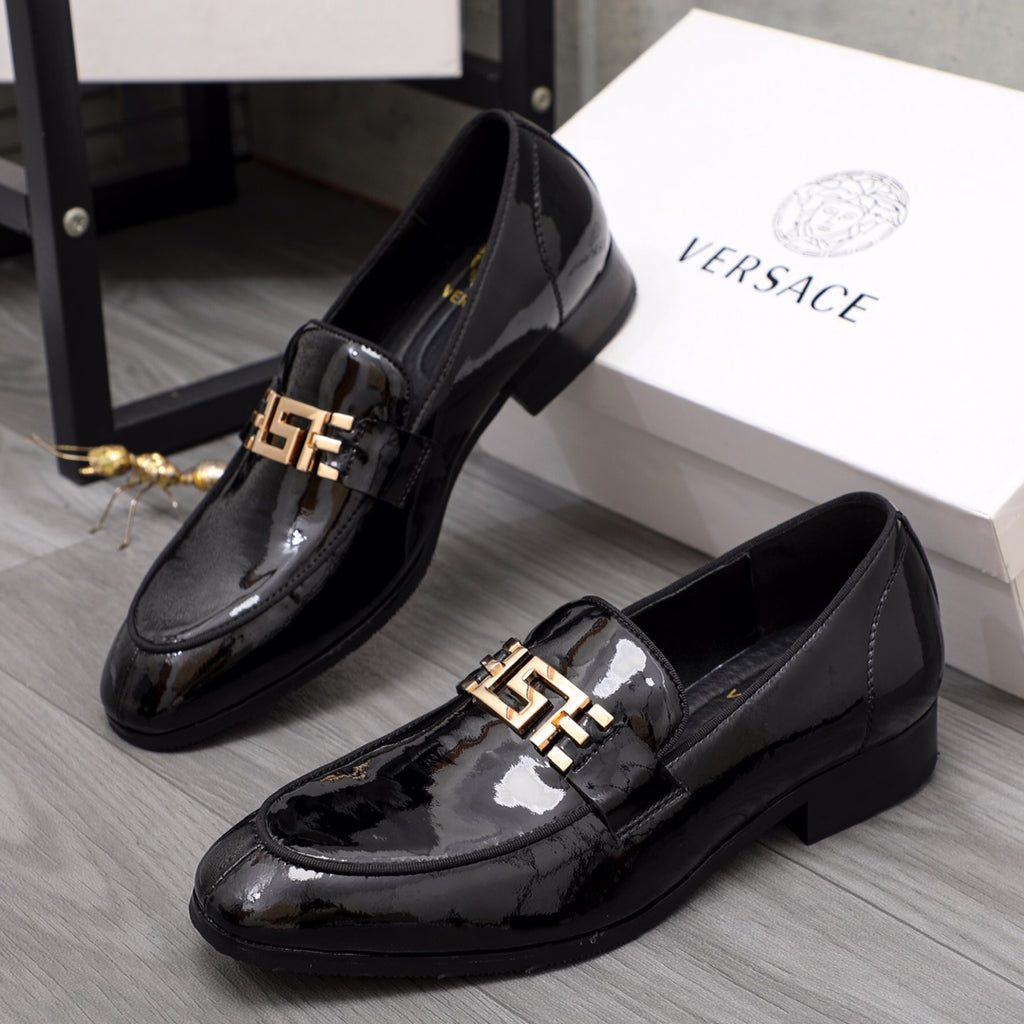 Versace black patent leather loafer pair with gold logo buckle on the front