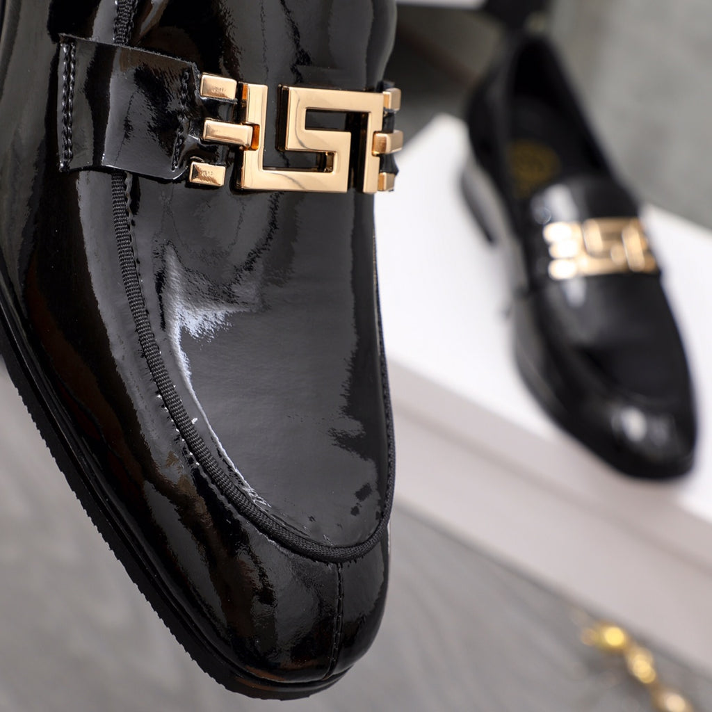 Versace black patent loafer close-up of gold logo buckle on vamp