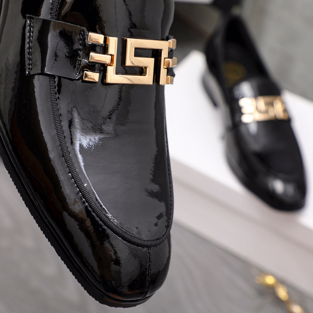 Versace black patent loafer close-up of gold logo buckle on vamp
