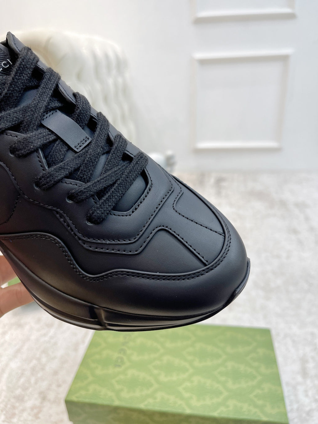 Gucci unisex sneaker close-up with dark leather laces, stitching, and logo detail