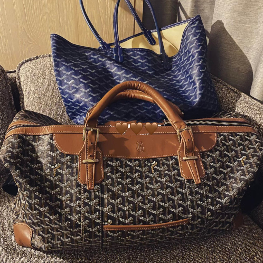 Tote bag with patterned monogram fabric, tan leather handles, and zippered top section.