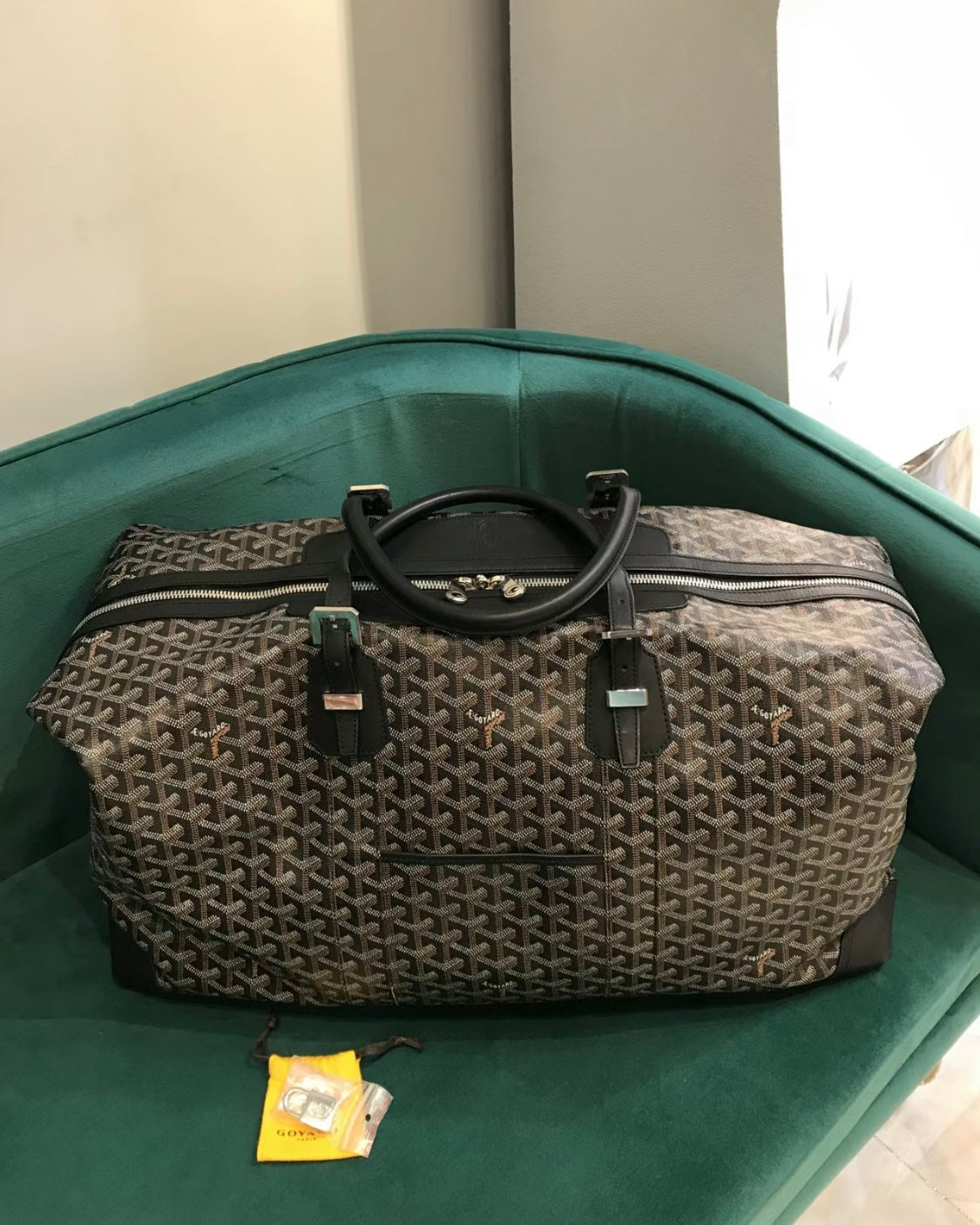 Tote bag with gray monogram pattern, black top handles, and adjustable shoulder strap.
