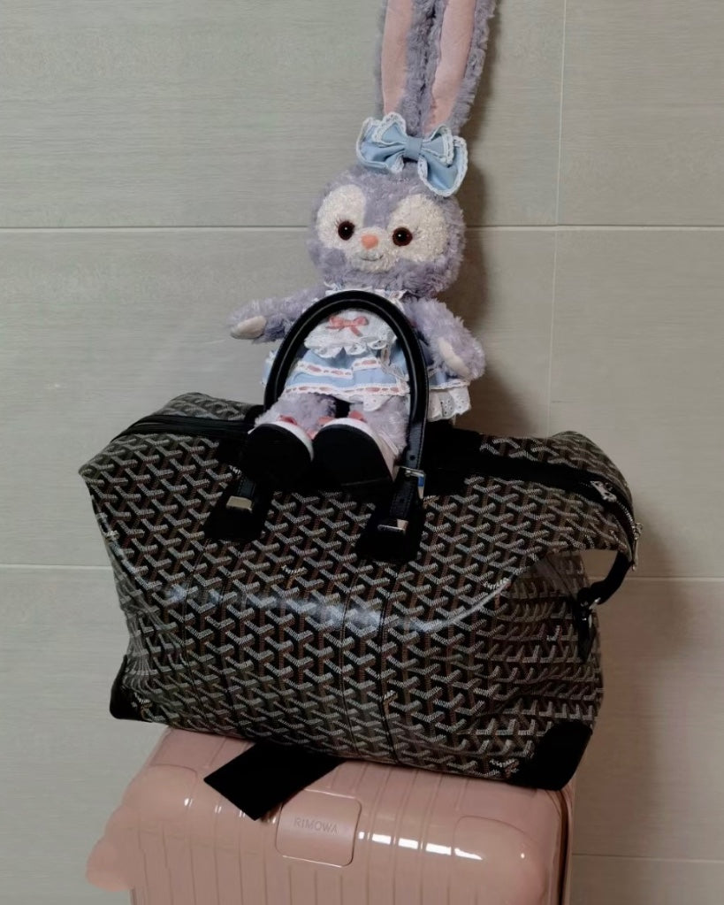 Tote bag with dark monogram pattern, top handles, and adjustable shoulder strap.