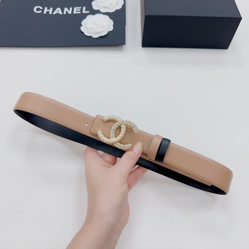 Tan belt with navy lining and gold-tone double-C crystal buckle, held flat