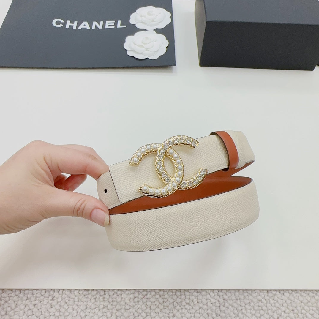 Chanel belt held in hand: beige strap with orange edge and gold-tone CC clasp.
