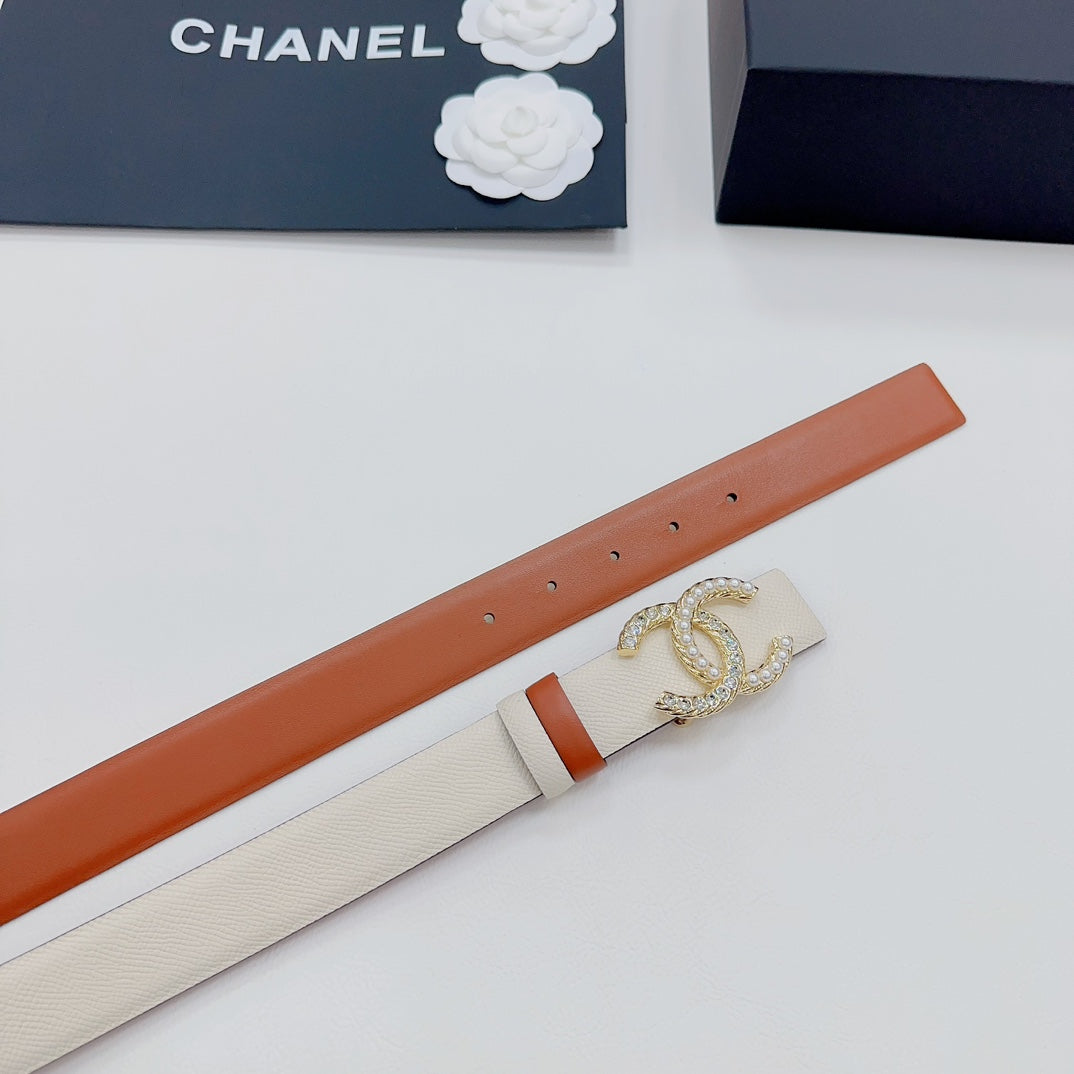 Chanel belt side detail: beige textured strap with orange backing and gold CC buckle.