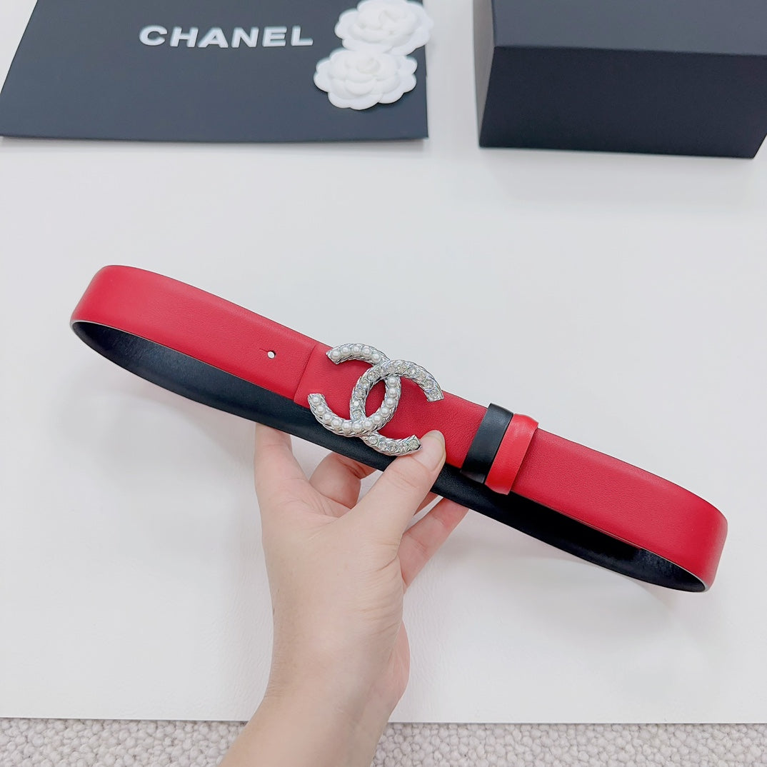 Chanel red belt held in hand; silver-tone CC buckle with black keeper stripe.