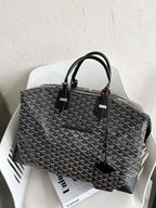 Tote bag with dark monogram pattern, black top handles, and zipper top closure.