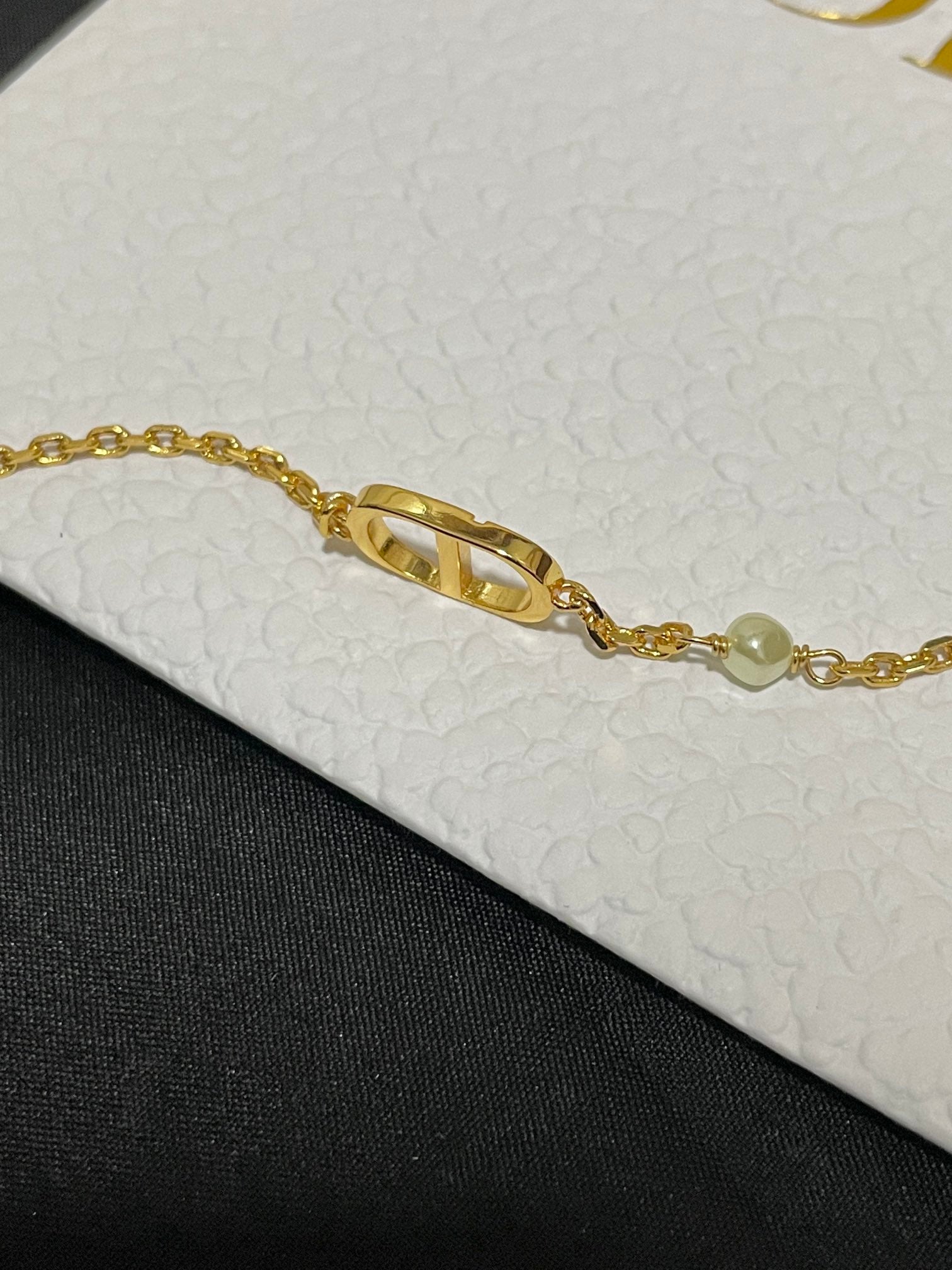 Gold-tone chain bracelet with elongated Dior logo charm and bead accents
